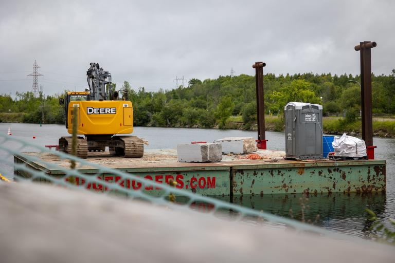 Barge on Otonabee River with yellow digger on it.